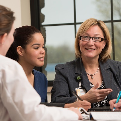 A woman smiles while talking with two people at a table.